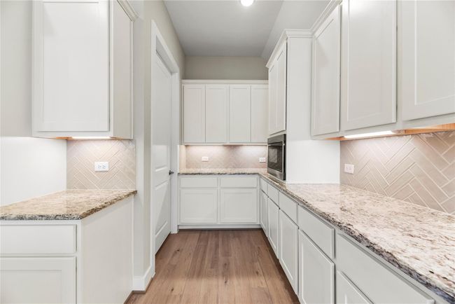 Wall-to-wall cabinets provide abundant storage and organization, while the walk-in pantry adds even more space to keep everything within easy reach making this kitchen as functional as it is stylish. | Image 19