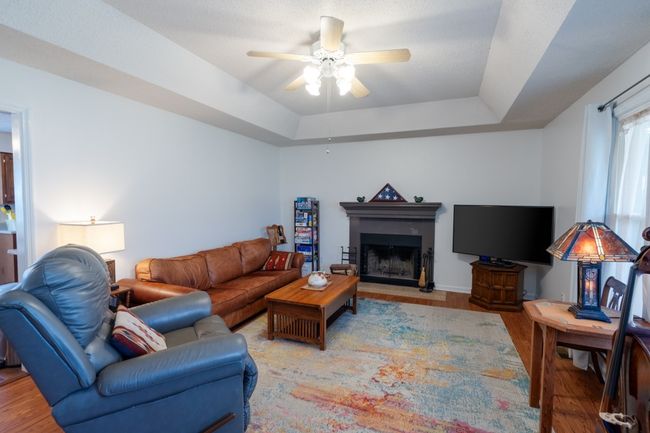 Living room with tray ceiling and wood-burning fireplace | Image 5