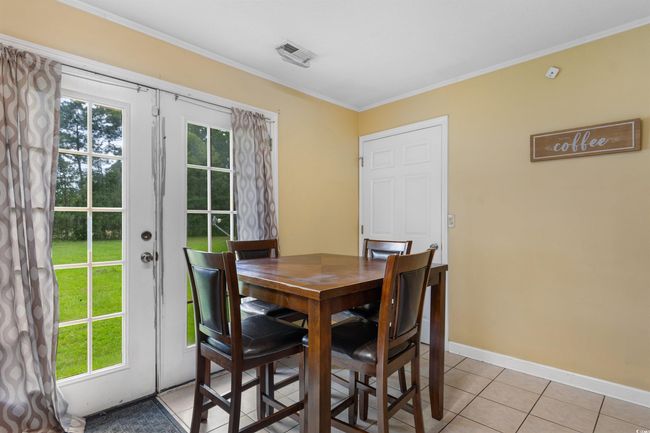 Kitchen featuring white appliances, light tile patterned flooring, crown molding, and light countertops | Image 10