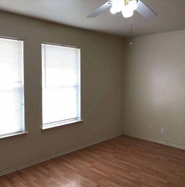 Unfurnished room with plenty of natural light, wood finished floors, a ceiling fan, and baseboards | Image 10
