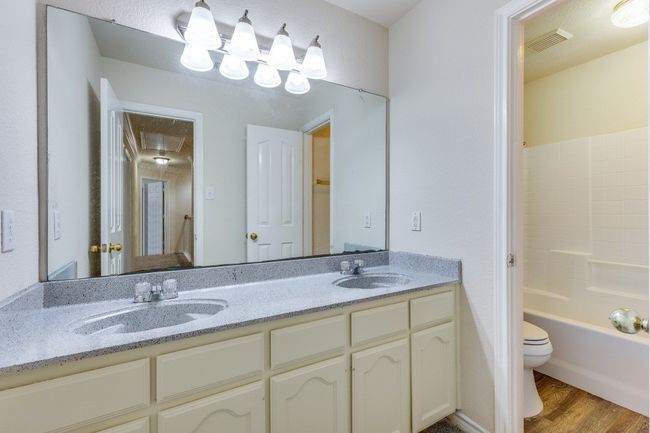 Full bathroom with visible vents, a sink, toilet, and wood finished floors | Image 23