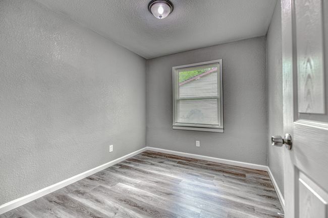 Empty room with wood finished floors, a textured ceiling, and a textured wall | Image 23
