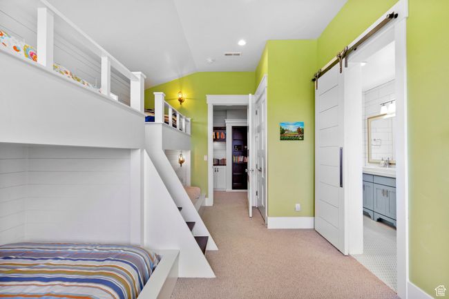 Carpeted bedroom featuring a barn door, visible vents, baseboards, and lofted ceiling | Image 48