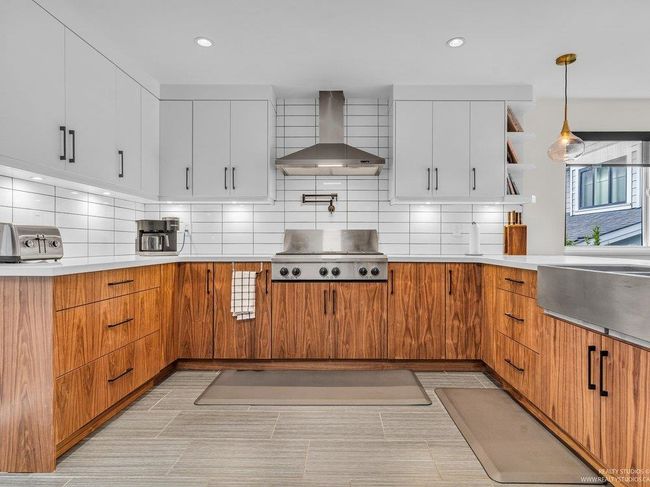 Huge chef's kitchen with 2025 new & updated cabinetry, gleaming white quartz counters, over the stove pot filler, gorgeous new backsplash, stainless steel appliances including fridge, dishwasher, 6 burner gas stove, wall oven, microwave & an apron sink. | Image 17