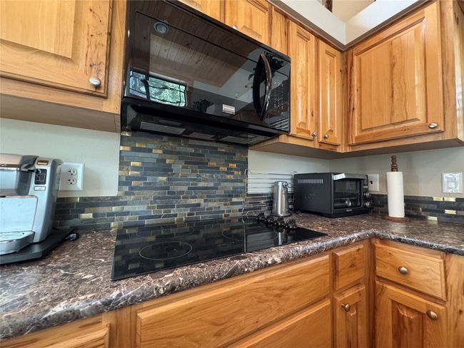 Kitchen with black appliances, backsplash, brown cabinets, and dark stone counters | Image 30