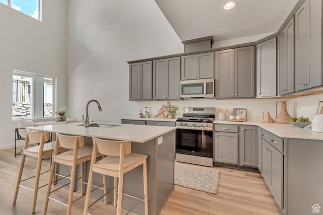 Kitchen featuring a sink, a wealth of natural light, gray cabinets, a towering ceiling, and appliances with stainless steel finishes | Image 4