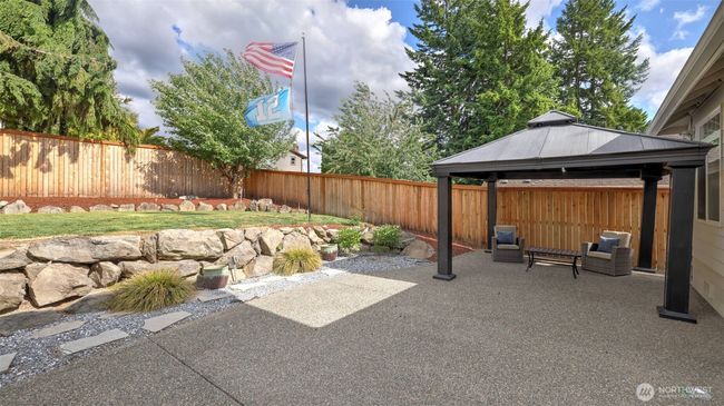 Step out onto the concrete backyard area featuring a spacious, dark-toned gazebo that remains with the home. Plenty of room to relax, enjoy the outdoors, and host gatherings or BBQs | Image 31