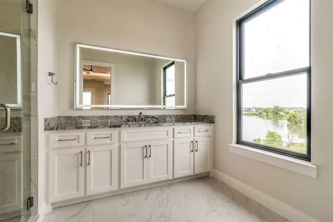 Bathroom with tile floors, a shower with shower door, a water view, and vanity | Image 26