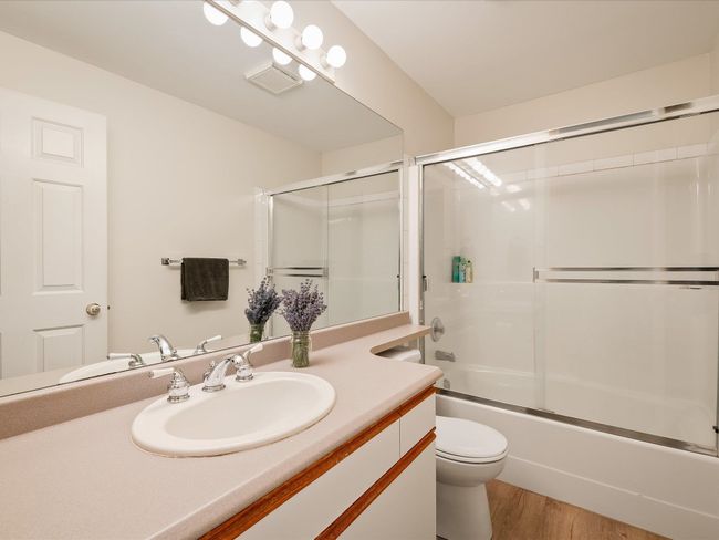 Bathroom with vanity, visible vents, toilet, wood finished floors, and combined bath / shower with glass door | Image 23