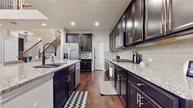 Kitchen with light stone countertops, dark brown cabinetry, dark wood finished floors, stainless steel appliances, and recessed lighting | Image 17