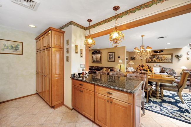 Kitchen featuring open floor plan, dark stone countertops, a peninsula, and light tile patterned floors | Image 11