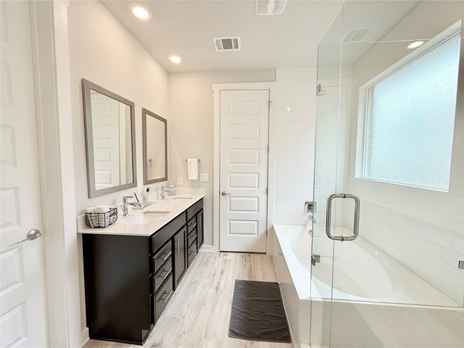 Full bathroom featuring a sink, double vanity, tiled tub, and visible vents | Image 20