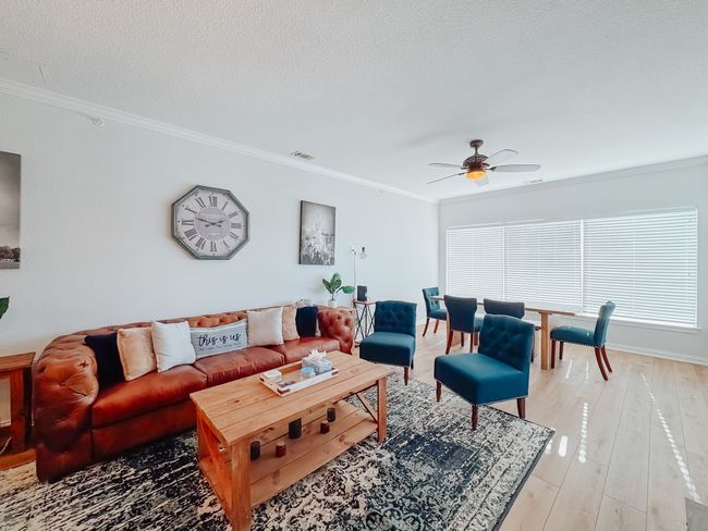 Living room with visible vents, a ceiling fan, a textured ceiling, crown molding, and light wood-style floors | Image 11