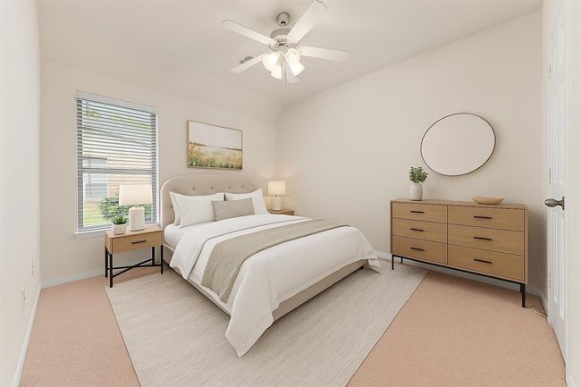 This light-filled secondary bedroom features a vaulted ceiling, neutral tones, and a large window overlooking the side yard. A ceiling fan and generous wall space make it a comfortable and versatile retreat for guests, children, or a home office. virtually staged | Image 31