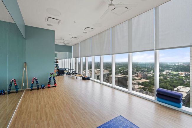 Gym with a ceiling fan, wood finished floors, a high ceiling, and plenty of natural light | Image 38