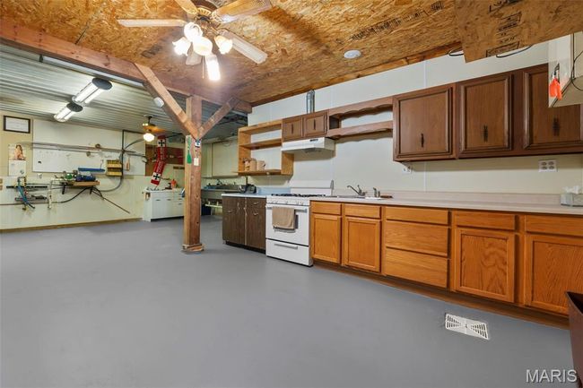 Kitchen with open shelves, white range with gas cooktop, concrete flooring, a ceiling fan, and light countertops | Image 31