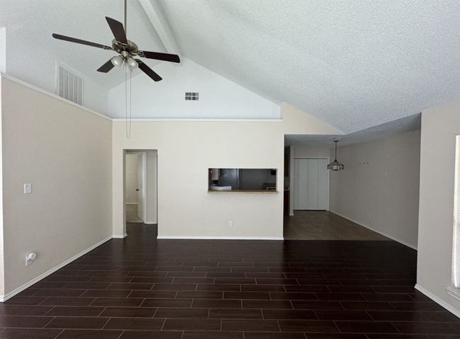 Unfurnished living room featuring high vaulted ceiling, dark wood-type flooring, ceiling fan, and beamed ceiling | Image 6