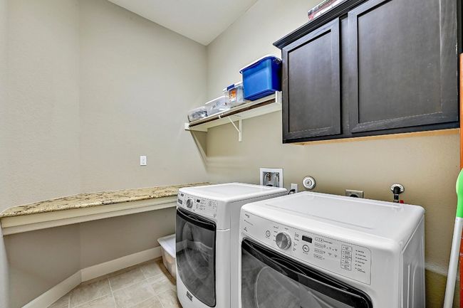 Laundry room with washing machine and clothes dryer, cabinets, shelf, and granite ironing platform | Image 34