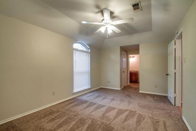 Unfurnished bedroom featuring light carpet, ensuite bath, and a ceiling fan | Image 17