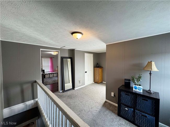 Second floor hallway with carpet, a decorative wall, and a textured ceiling | Image 21