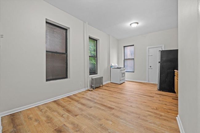 Empty room with radiator heating unit and light wood finished floors | Image 11