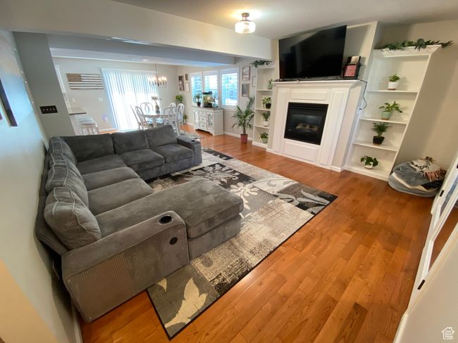 Living area featuring a chandelier, wood finished floors, and a glass covered fireplace | Image 4