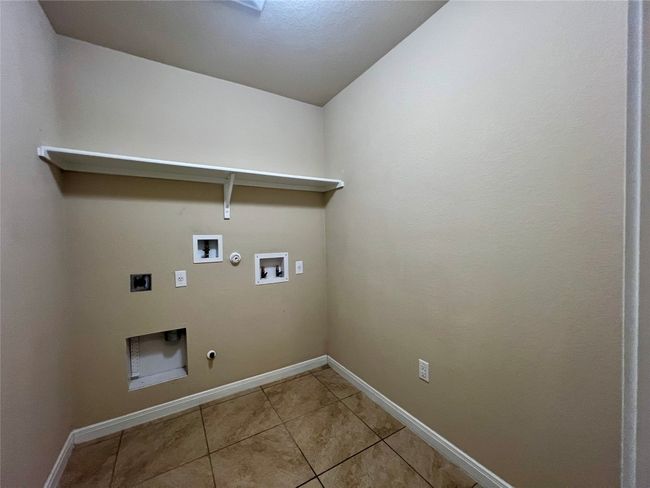 Laundry room featuring gas dryer hookup, electric dryer hookup, washer hookup, tile patterned flooring, and baseboards | Image 28
