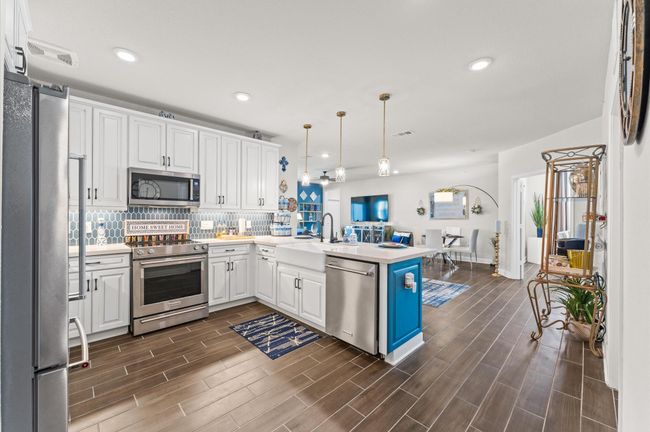 A seamless layout extends from the gourmet kitchen into the dining area, offering beautiful pendant lighting and luxury flooring. | Image 4