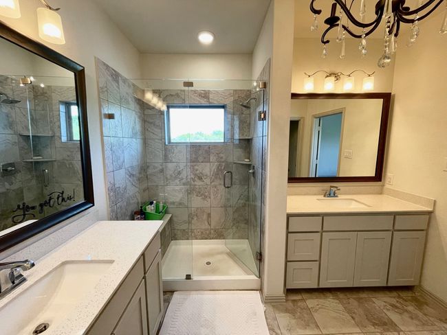 Bathroom featuring a tile shower, marble finish floors, two vanities, a chandelier, and ensuite bath | Image 18