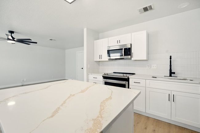 Kitchen featuring appliances with stainless steel finishes, a large basin sink, white shaker cabinetry, ceiling fan, beautiful gold quartz countertops and decorative herringbone​​‌​​​​‌​​‌‌​‌‌​​​‌‌​​‌‌​‌​​​​​‌ backsplash | Image 4