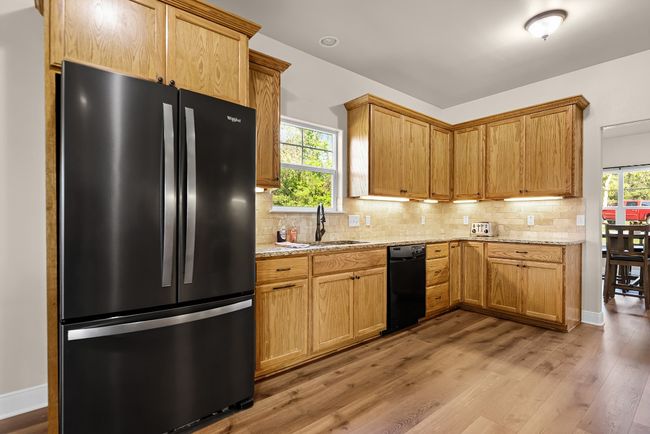 Kitchen featuring tasteful backsplash, black dishwasher, freestanding refrigerator, and a sink | Image 11