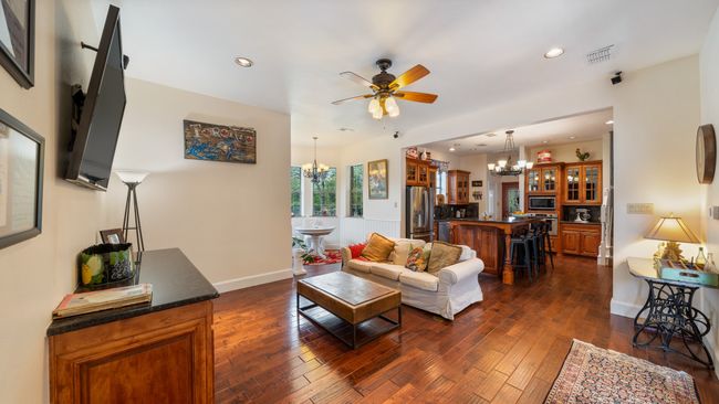 Living room with dark wood-style floors, recessed lighting, ceiling fan with notable chandelier, and visible vents | Image 13