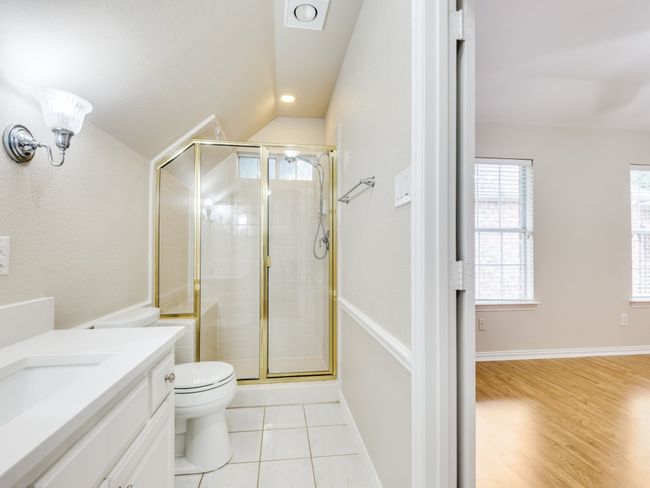 Freshly painted Bathroom featuring a shower, vanity with new marble counter and undermount sink, lofted ceiling, and tile patterned floors | Image 24