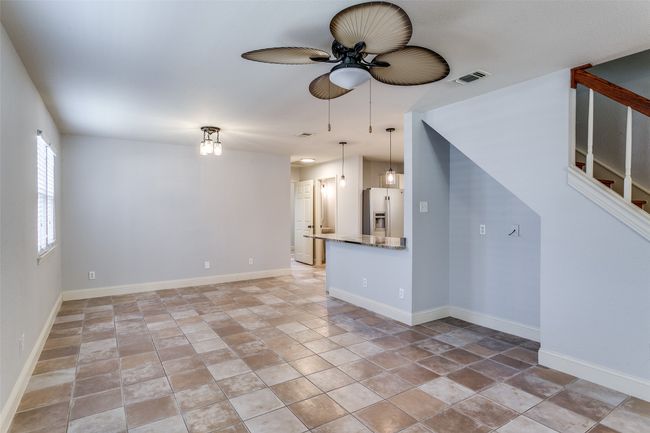 Unfurnished living room with stone tile floors, ceiling fan, and stairs | Image 9