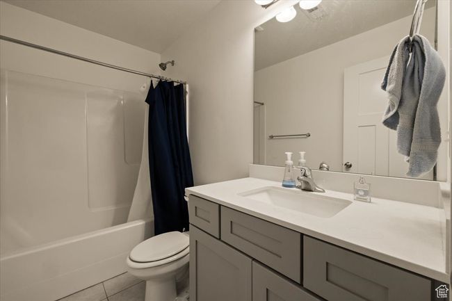 Full bathroom with toilet, vanity, tile patterned floors, and shower / bathtub combination with curtain | Image 23