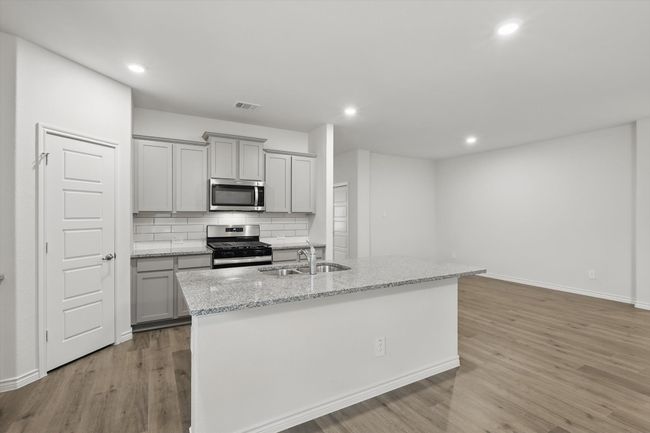 Kitchen featuring appliances with stainless steel finishes, gray cabinetry, light wood-style floors, backsplash, and recessed lighting | Image 14