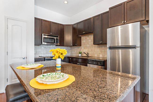Kitchen featuring appliances with stainless steel finishes, dark brown cabinetry, decorative backsplash, a sink, and recessed lighting | Image 6