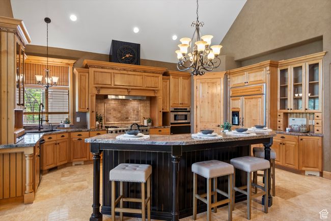 Kitchen with a chandelier, a sink, a breakfast bar area, a center island, and double oven | Image 35