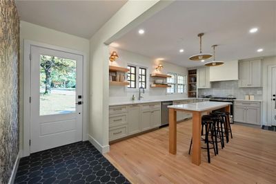 Kitchen featuring a kitchen bar, light wood-type flooring, a center island, hanging light fixtures, and stainless steel appliances | Image 3