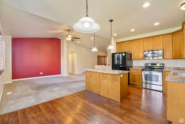 Kitchen with stainless steel appliances, dark wood-type flooring, a kitchen island, arched walkways, and a ceiling fan | Image 9