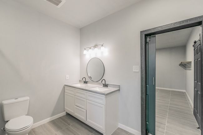 Bathroom featuring toilet, a sink, baseboards, visible vents, and double vanity | Image 14