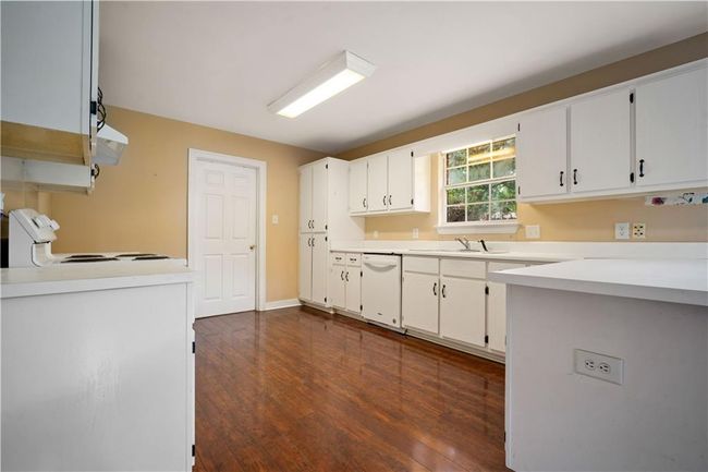 Kitchen with white dishwasher, range, dark wood-style floors, white cabinets, and light countertops | Image 10