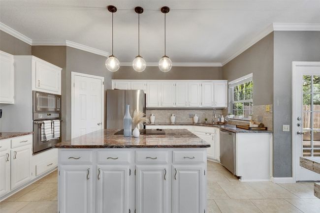 Kitchen featuring appliances with stainless steel finishes, a center island, tasteful backsplash, dark stone counters, and a sink | Image 10