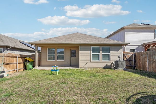 Rear view of property with central air condition unit, a lawn, a gate, a fenced backyard, and roof with shingles | Image 23