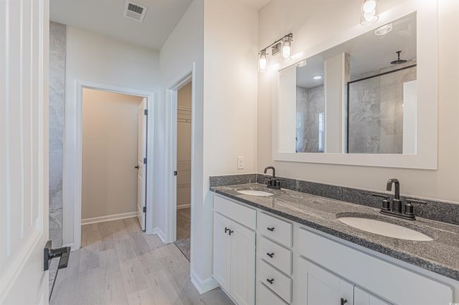 Bathroom featuring visible vents, a stall shower, a walk in closet, and a sink | Image 14
