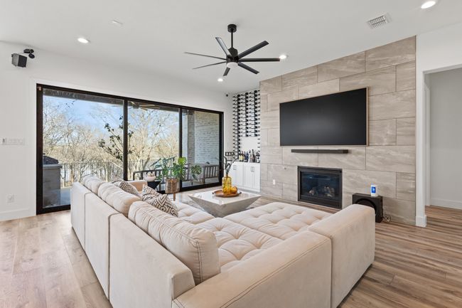 Living area featuring a ceiling fan, recessed lighting, a tiled fireplace, and light wood finished floors | Image 10