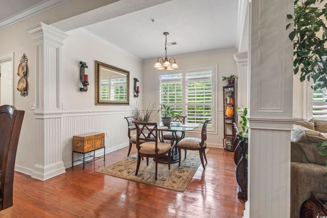 Dining area featuring healthy amount of natural light, wood-type flooring, a chandelier, crown molding, and wainscoting | Image 27
