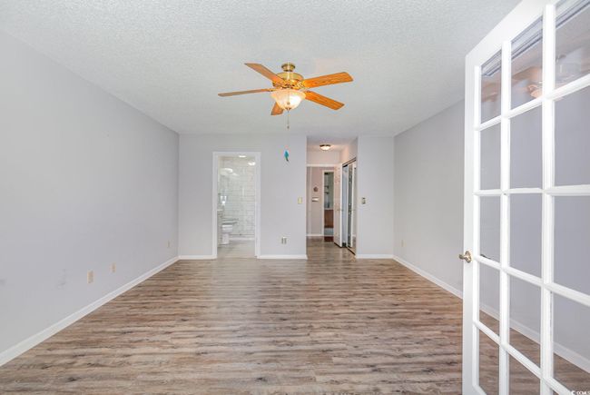 Empty room featuring ceiling fan, french doors, wood finished floors, and a textured ceiling | Image 23