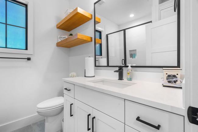 Full bathroom with vanity, toilet, a stall shower, baseboards, and tile patterned flooring | Image 24