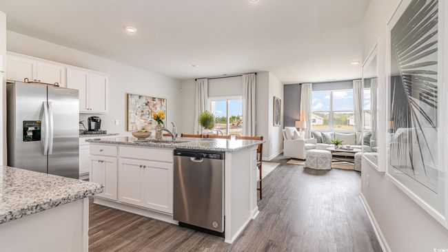 Kitchen with stainless steel appliances, dark wood-style floors, open floor plan, white cabinets, and an island with sink | Image 12